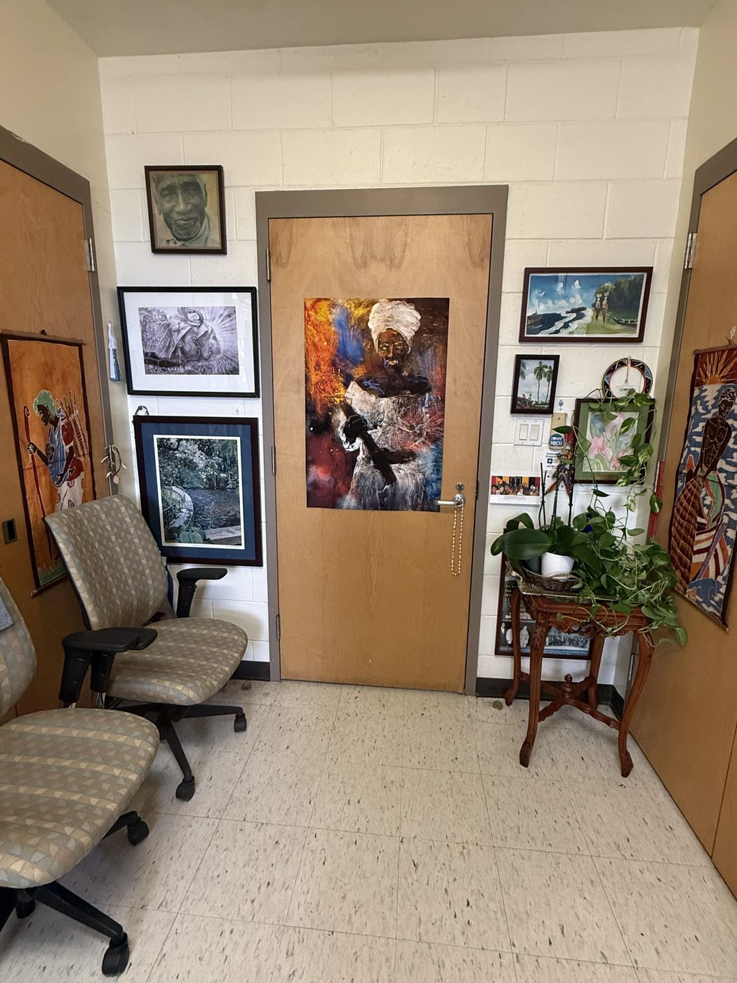 A hallway lined with framed Caribbean artwork and photography from the VICCC collection.