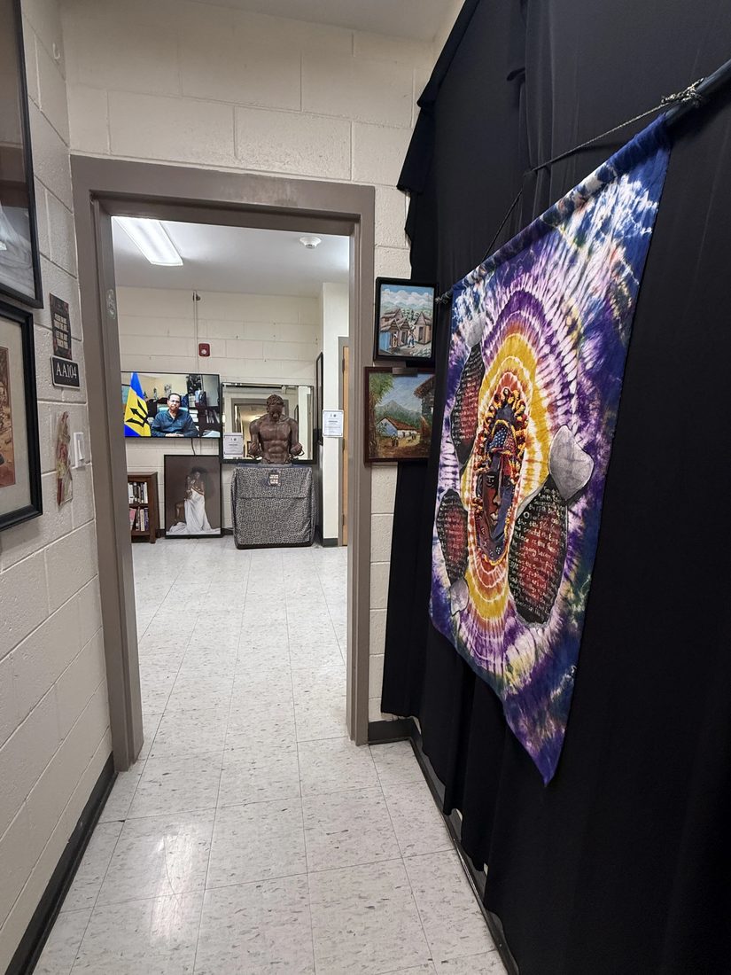 A hallway view into an exhibit space, with a colorful tie-dye banner hanging in the foreground.